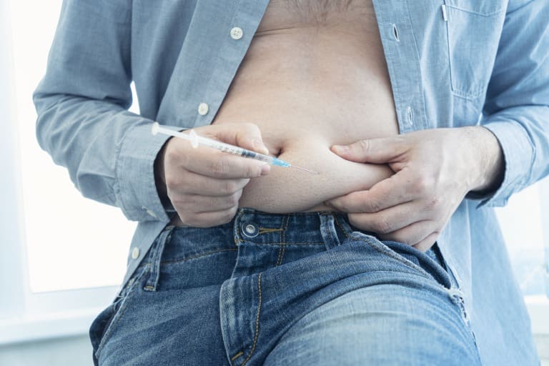 A man is holding his stomach and using an electronic device.