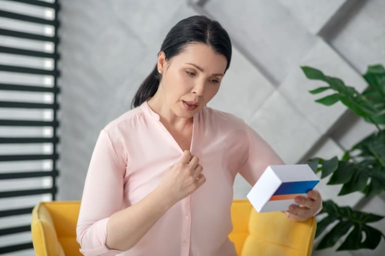 A woman holding onto a box and looking surprised.