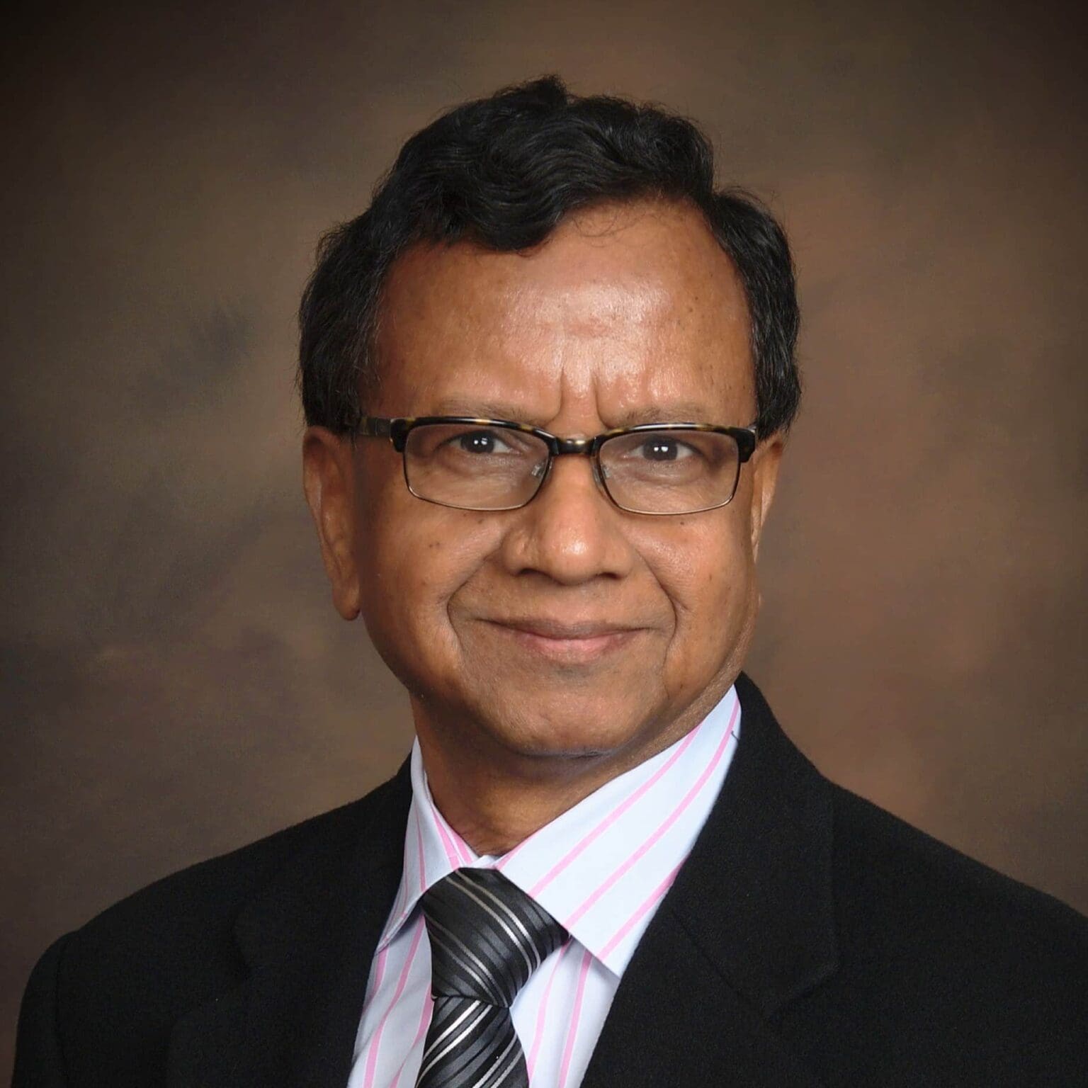 A man in a suit and tie standing up against a wall.