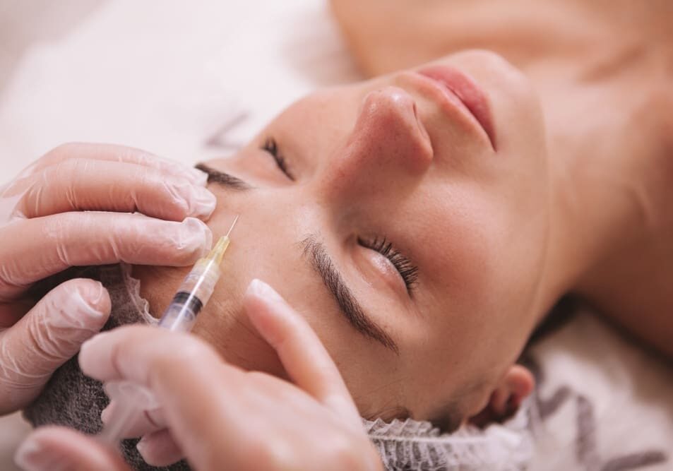 A woman getting her face waxed at the spa.