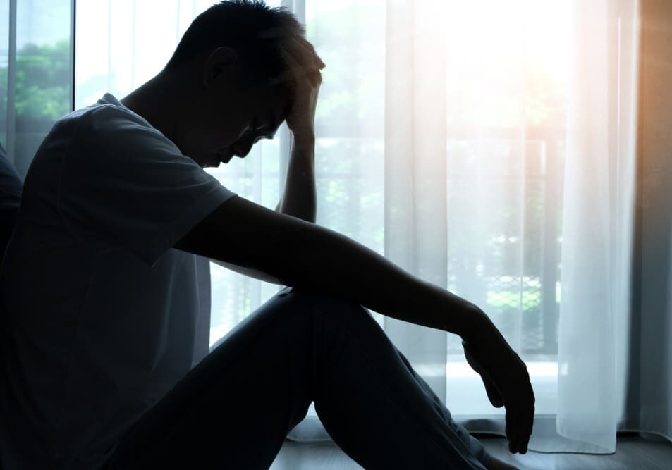 A man sitting on the ground with his head down.